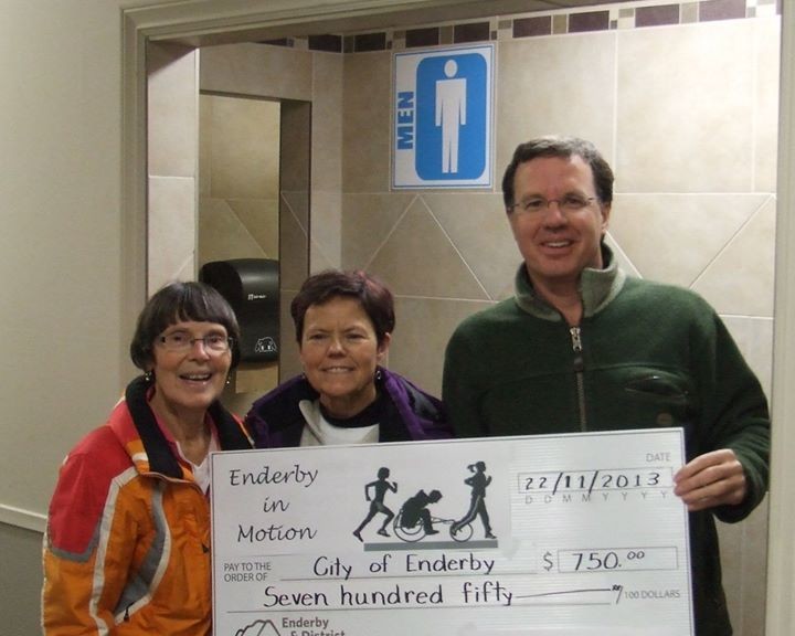 Enderby in Motion representatives present a cheque to Councillor Case for $750 towards accessibility improvements to the Enderby Arena washrooms.