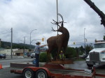 Majestic Metal Art's deer sculpture suspended in mid-air by Central Hardware's crane during installation in Enderby BC