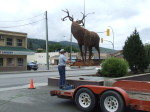 Majestic Metal Art's deer sculpture suspended in mid-air by Central Hardware's crane during installation in Enderby BC