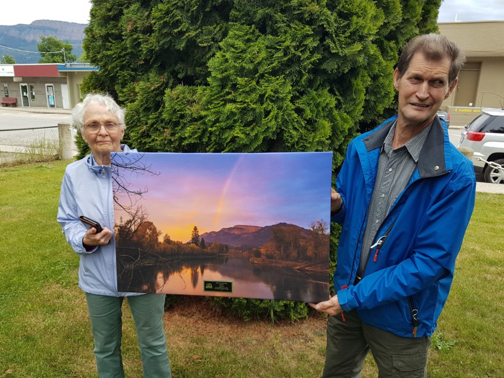 Melvin Slater, recipient of the City of Enderby Lifetime Civic Merit Award, holds the commemorative poster with his partner, Bev Gale.