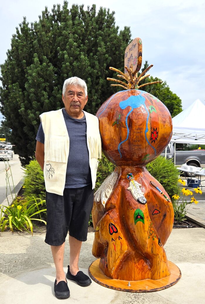 Splatsin artist Hop You beside his sculpture, Mother Earth, unveiled in the City of Enderby in July 2025.
